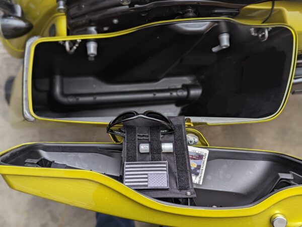 TactiTether black pouch inside a motorcycle storage compartment with various items stored