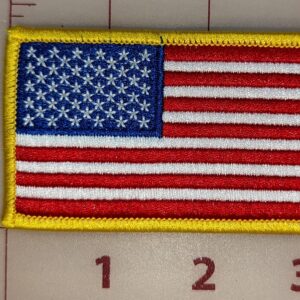 Close-up of TactiTether American flag patch with red, white, and blue colors, and a yellow border, placed on a measuring grid.