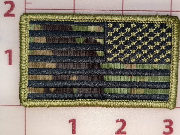 Camo American flag patch with green border and camouflage pattern on a gridded background.