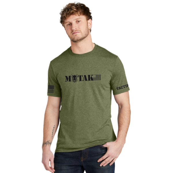 Front view of an olive green Tactipig t-shirt with a black Motak logo and text, featuring an American flag design on one sleeve and "TACTIPIG" text on the other sleeve.